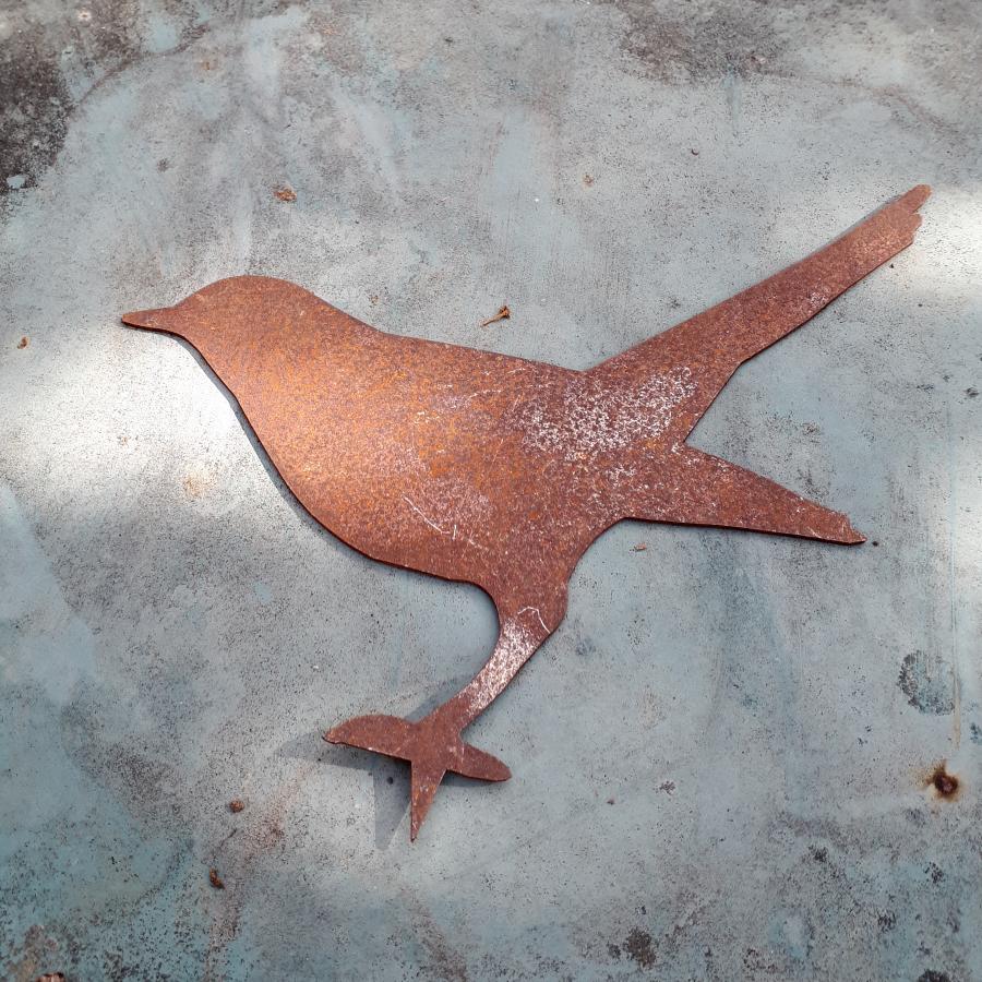 Oiseau merle debout avec pique en fer rouillé